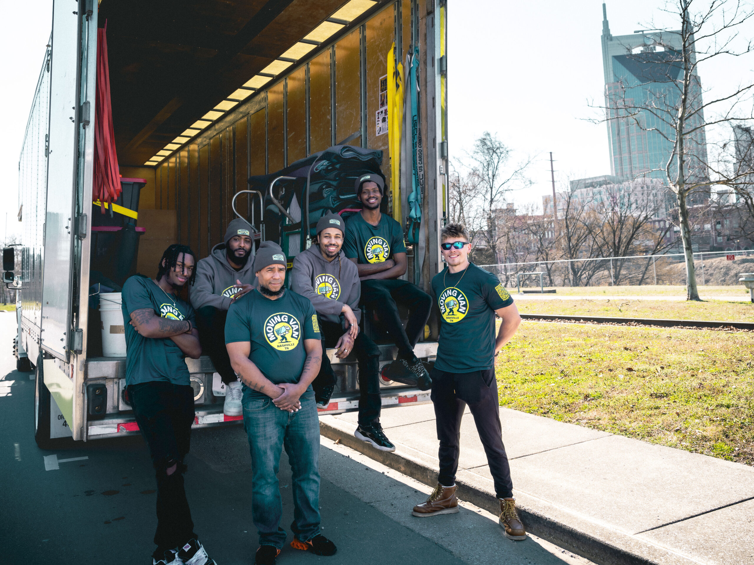A group of people standing on the back of a moving truck.