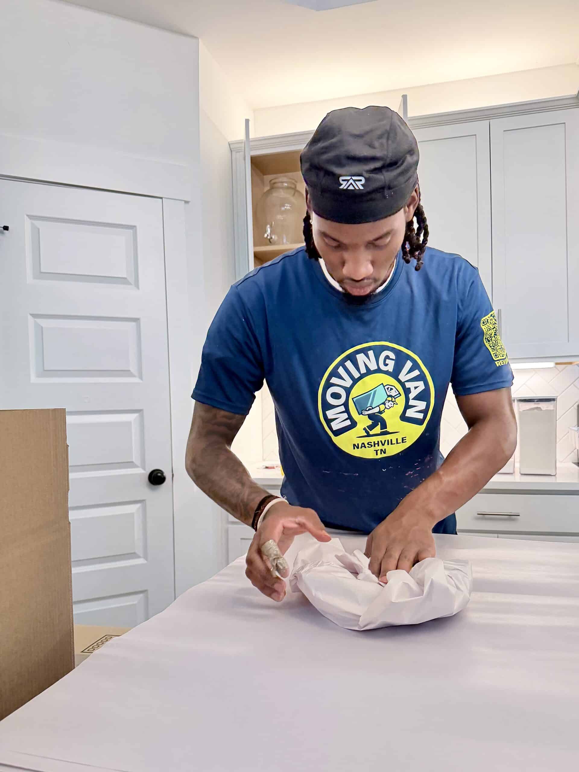 Moving Van mover carefully packing dishes.